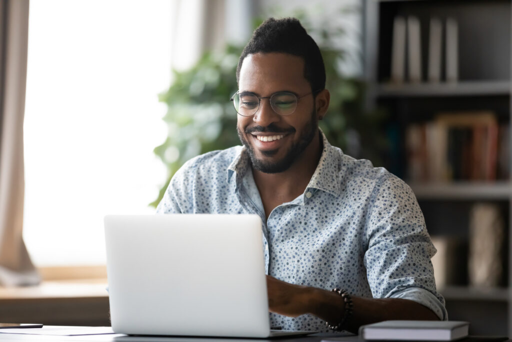 Man smiling while using laptop